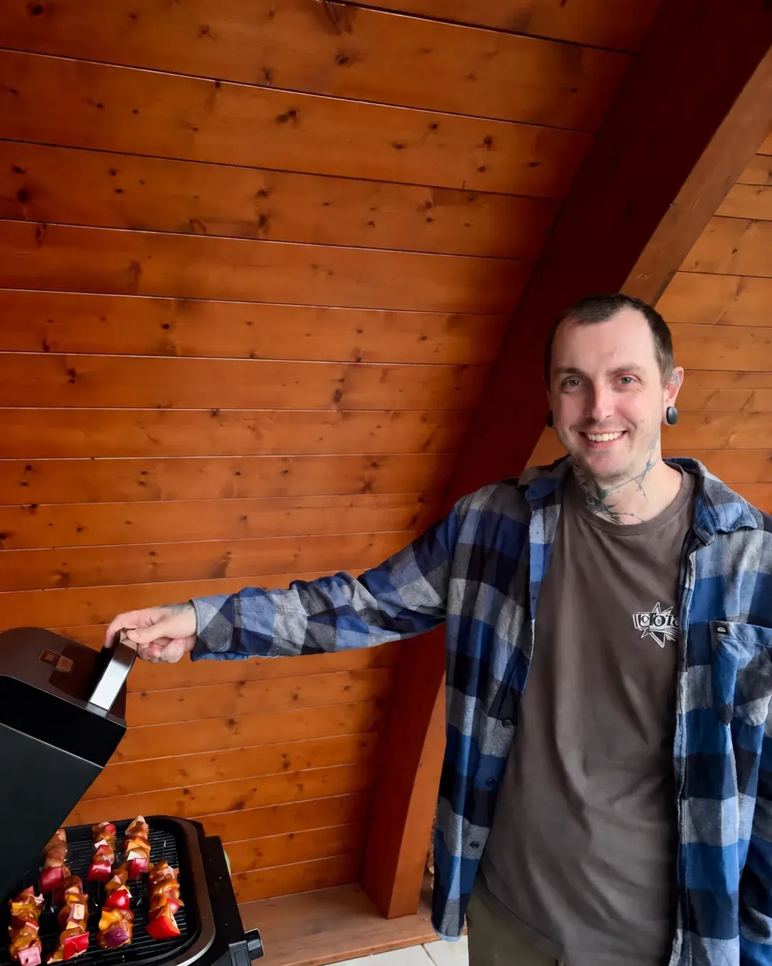 Bastien Billey, souriant, devant un barbecue sous un abri en bois