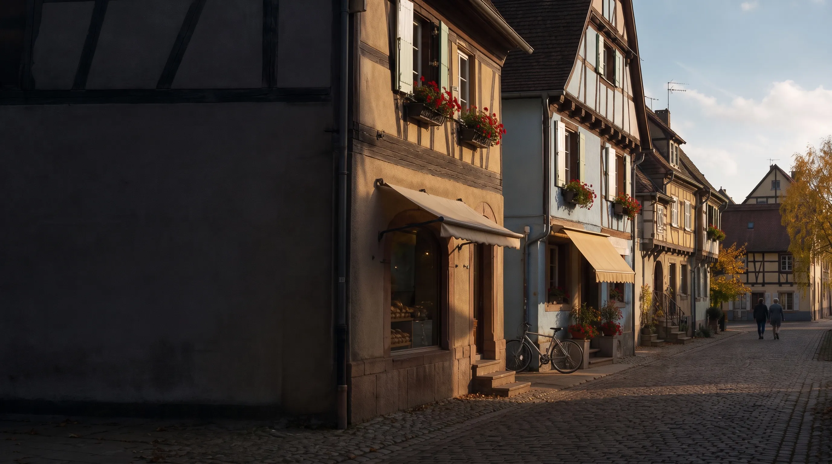 Une rue de village alsacien en fin de journée, avec ses maisons à colombages et ses petits commerces